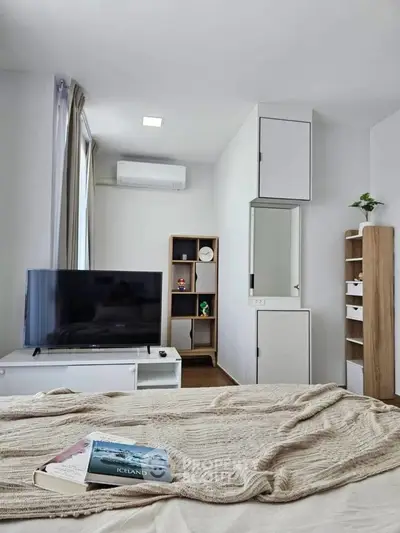 Modern bedroom with TV, air conditioning, and stylish shelving in a cozy apartment.