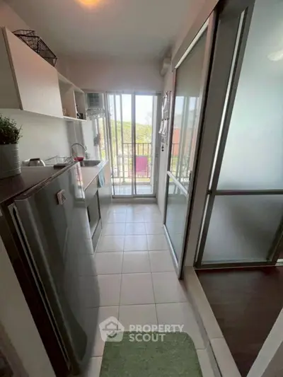 Modern kitchen with sleek design and balcony access, featuring stainless steel appliances and ample natural light.