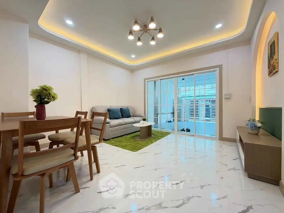 Modern living room with elegant lighting and sliding glass doors opening to a balcony.