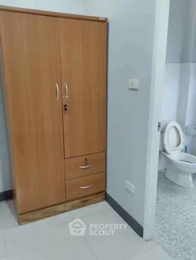 Compact bathroom with wooden cabinet and modern toilet