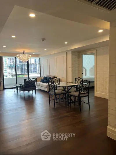 Spacious living room with elegant decor and city view, featuring hardwood floors and modern furniture.