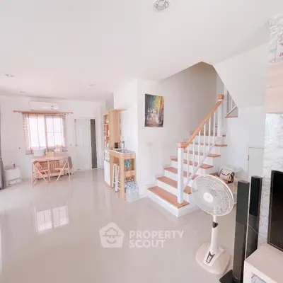 Spacious modern living room with staircase and dining area, bright and airy ambiance.