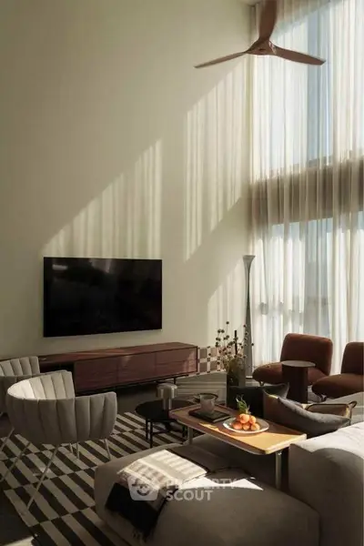 Luxurious living room with high ceilings, modern furniture, and large TV, bathed in natural light.