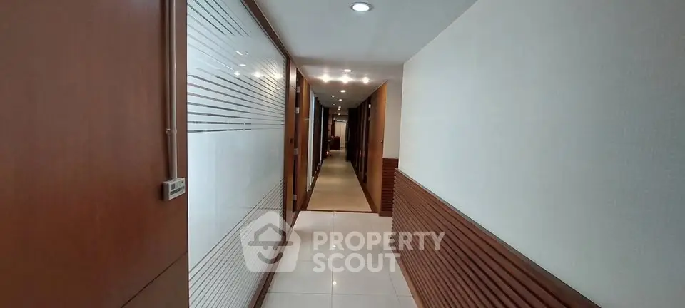Elegant corridor with modern wood paneling and recessed lighting in upscale building.