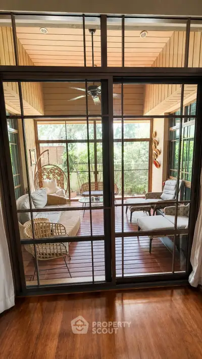 Stunning enclosed balcony with cozy seating and lush garden view, perfect for relaxation and entertaining.