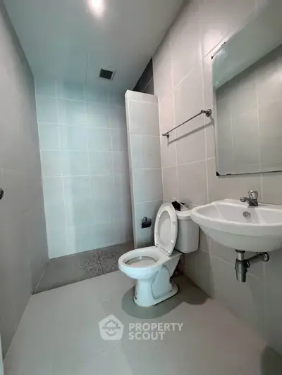 Modern bathroom with sleek design and tiled walls, featuring a toilet and sink.