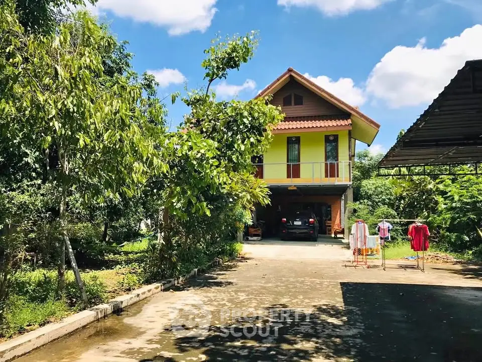 Charming two-story house with lush garden and spacious driveway under a clear blue sky.