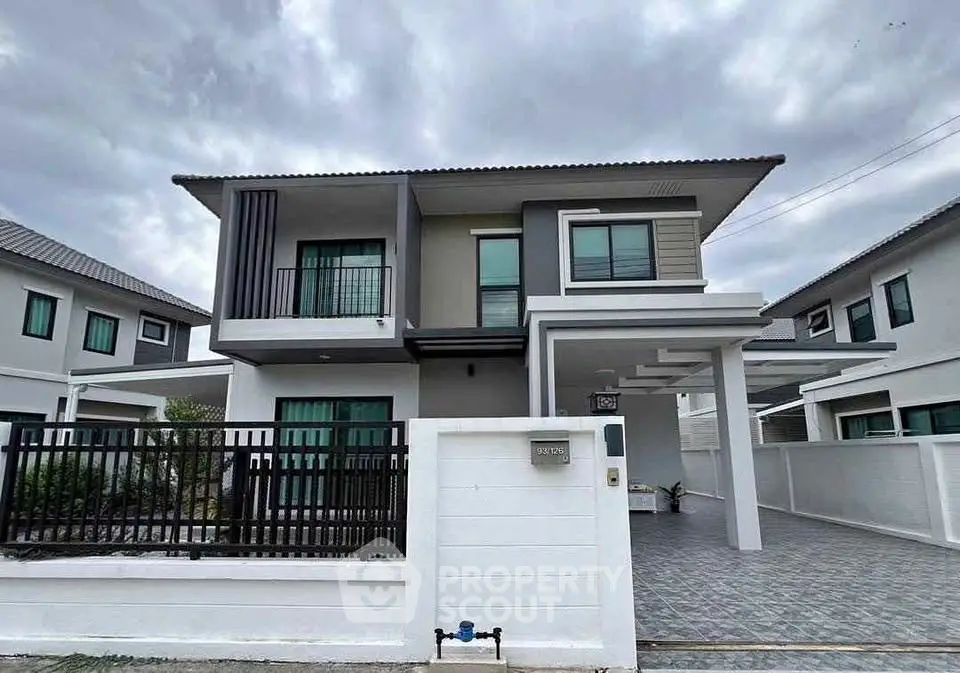 Modern two-story house with sleek design and spacious driveway in suburban neighborhood.