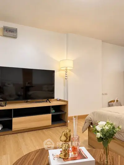 Modern bedroom with stylish decor and wooden flooring, featuring a TV and cozy lighting.