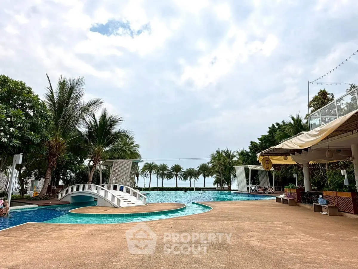 Luxurious resort-style pool with palm trees and ocean view, perfect for relaxation and leisure.
