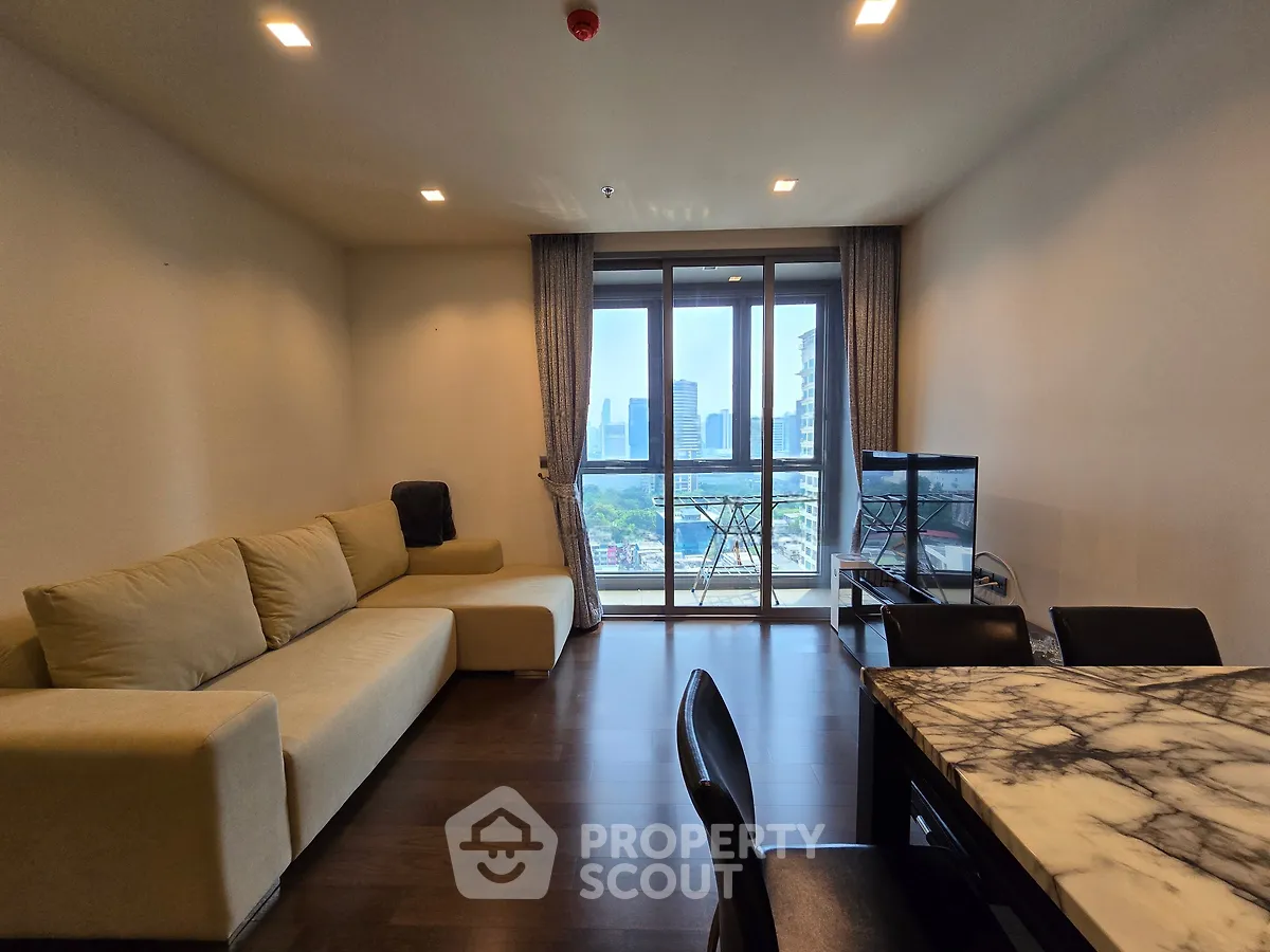 Spacious living room with modern furniture and city view balcony, perfect for urban living.