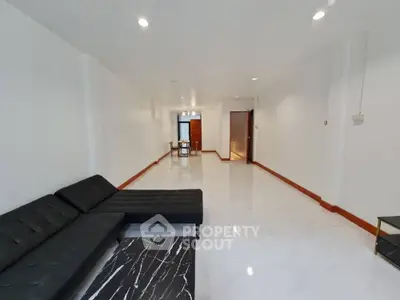 Spacious modern living room with sleek black sofa and marble flooring, perfect for contemporary living.