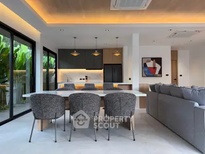 Modern open-plan living room with stylish dining area and sleek kitchen design, featuring large windows and elegant lighting.
