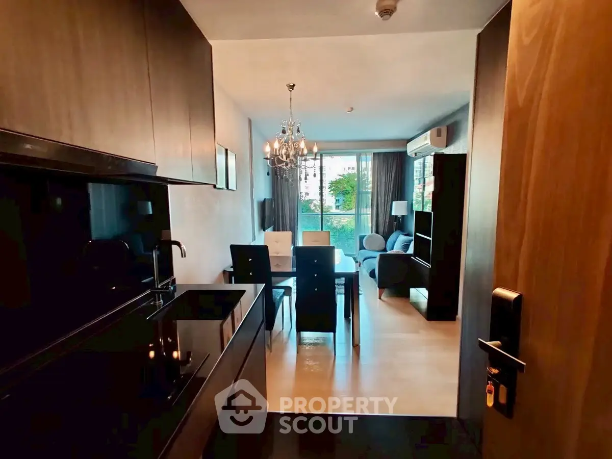 Modern open-layout kitchen and living room with elegant chandelier and garden view.