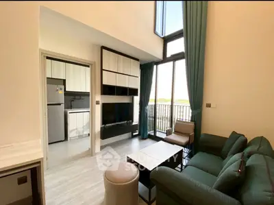 Modern living room with high ceiling and large windows, featuring stylish furniture and open kitchen view.