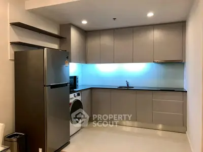 Modern kitchen with sleek cabinets, stainless steel fridge, and built-in washing machine.