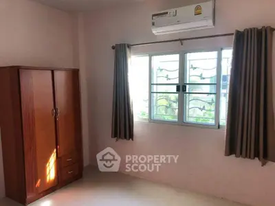 Bright bedroom with air conditioning and wardrobe, featuring natural light through window.