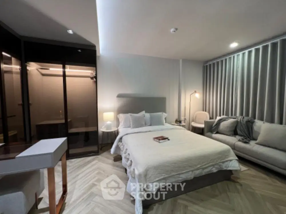 Modern bedroom with elegant decor and cozy seating area, featuring a stylish bed and ambient lighting.