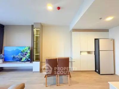 Modern living room with sleek furniture and large TV, featuring open layout and stylish decor.
