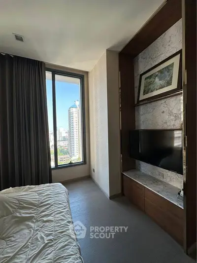 Modern bedroom with large window and city view, featuring a wall-mounted TV and elegant decor.