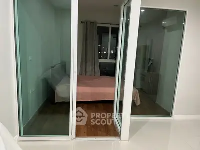 Modern bedroom with glass sliding doors and city view, featuring minimalist design and wooden flooring.