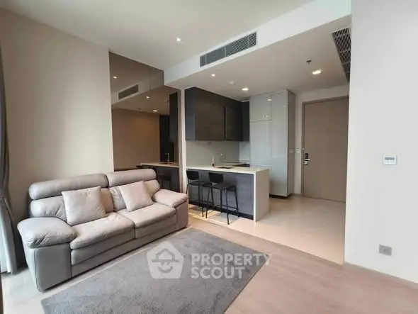 Modern living room with sleek kitchen and cozy sofa in open layout apartment.