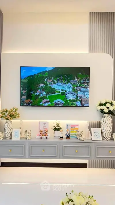Elegant living room with modern decor and wall-mounted TV displaying scenic view.