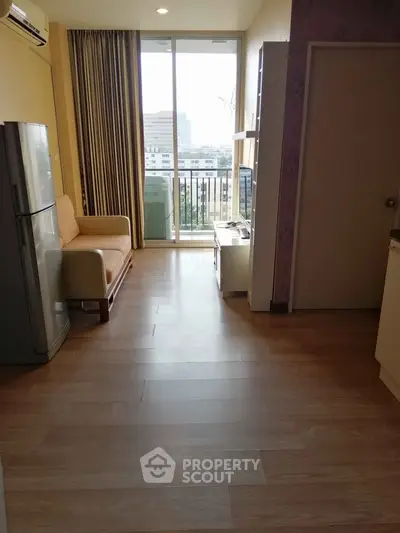 Bright living room with balcony view, featuring modern furniture and wooden flooring.