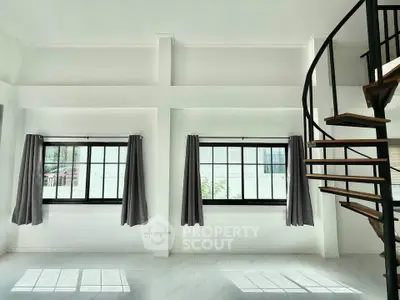 Spacious modern living room with spiral staircase and large windows, perfect for natural light lovers.