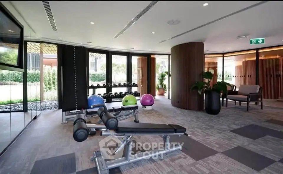 Luxurious gym with modern equipment and serene garden view in upscale residential building.