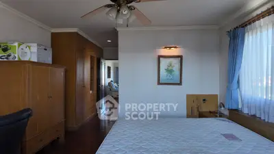 Spacious bedroom with wooden furniture and large window for natural light