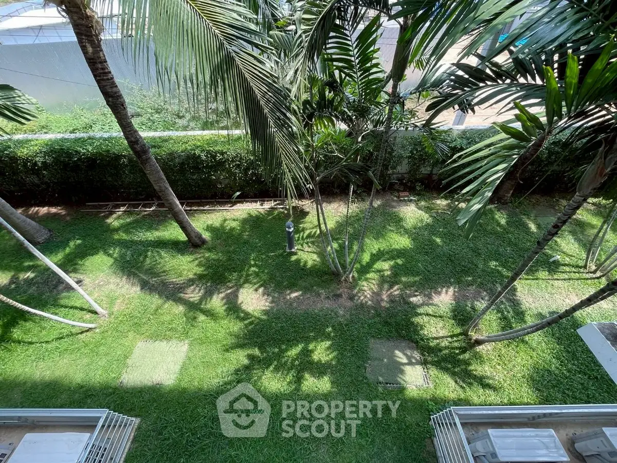 Lush garden view with palm trees and manicured lawn, perfect for relaxation.