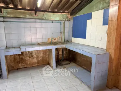 Spacious kitchen with tiled countertops and rustic charm, ready for renovation.