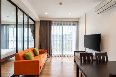 Modern living room with orange sofa, glass partition, and large window view.