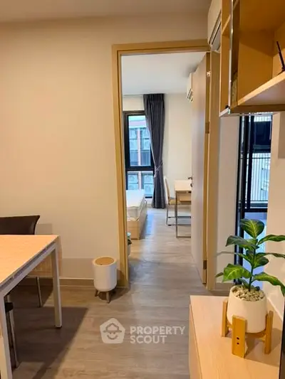 Modern apartment interior with open layout, featuring a cozy living area and a view into a bright bedroom.