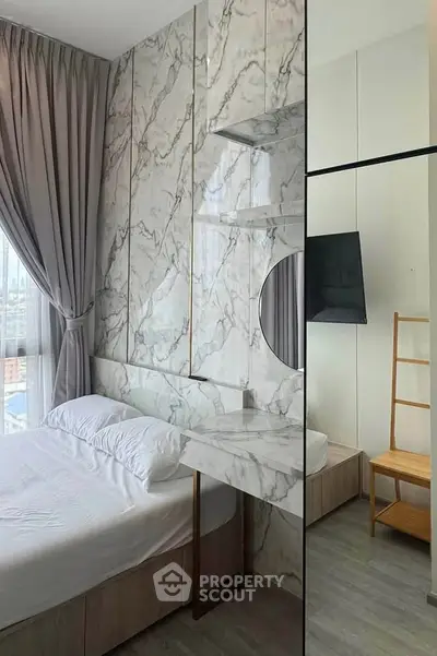 Modern bedroom with marble accent wall and large window, featuring sleek decor and natural light.