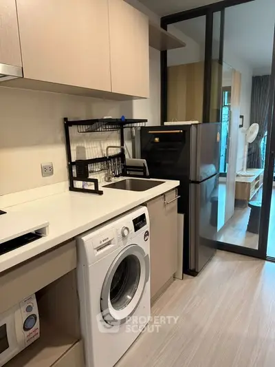 Modern kitchen with washing machine and fridge in sleek apartment