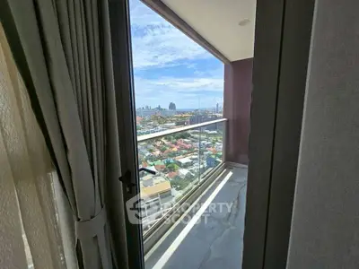 Stunning city view from a high-rise balcony with glass railing and elegant curtains.