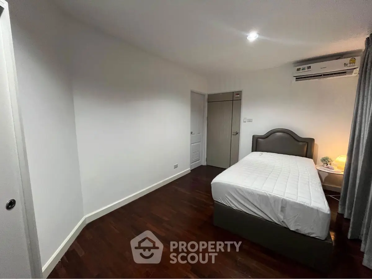 Cozy bedroom with wooden flooring and modern air conditioning unit