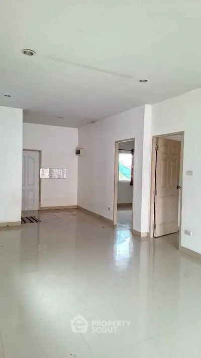 Spacious empty room with white walls and tiled flooring, ready for customization.