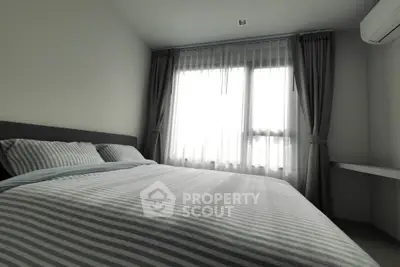 Cozy bedroom with striped bedding and large window for natural light.