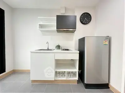 Modern minimalist kitchen with sleek cabinetry and compact fridge