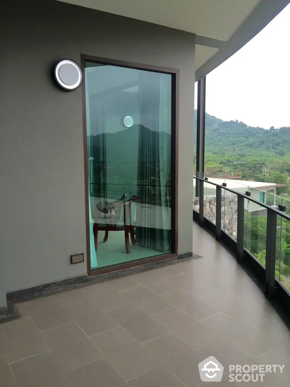 Spacious balcony with panoramic hillside views, featuring sleek floor tiles and a modern glass barrier, perfect for outdoor relaxation and entertaining.