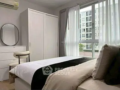 Modern bedroom with large window and stylish decor in urban apartment.