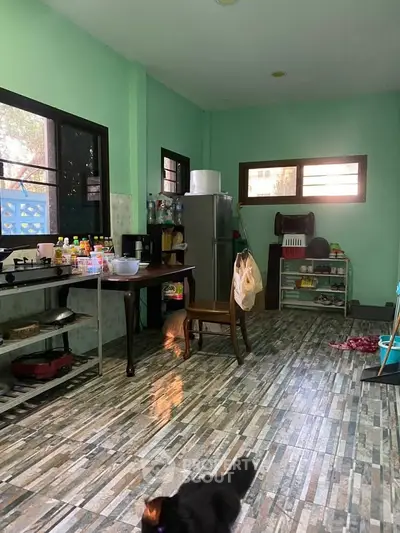 Spacious kitchen with green walls and tiled flooring, featuring a fridge and open shelving.