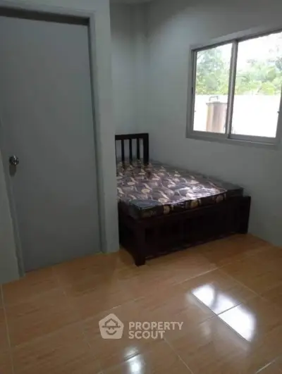 Cozy bedroom with wooden bed frame and window view, ideal for restful nights.