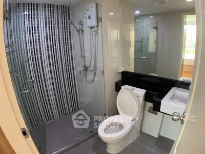 Modern bathroom with glass shower and sleek fixtures in a contemporary apartment.