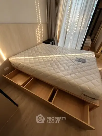 Modern bedroom with storage bed and sunlight streaming through curtains.