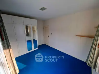 Spacious bedroom with blue carpet and mirrored wardrobe