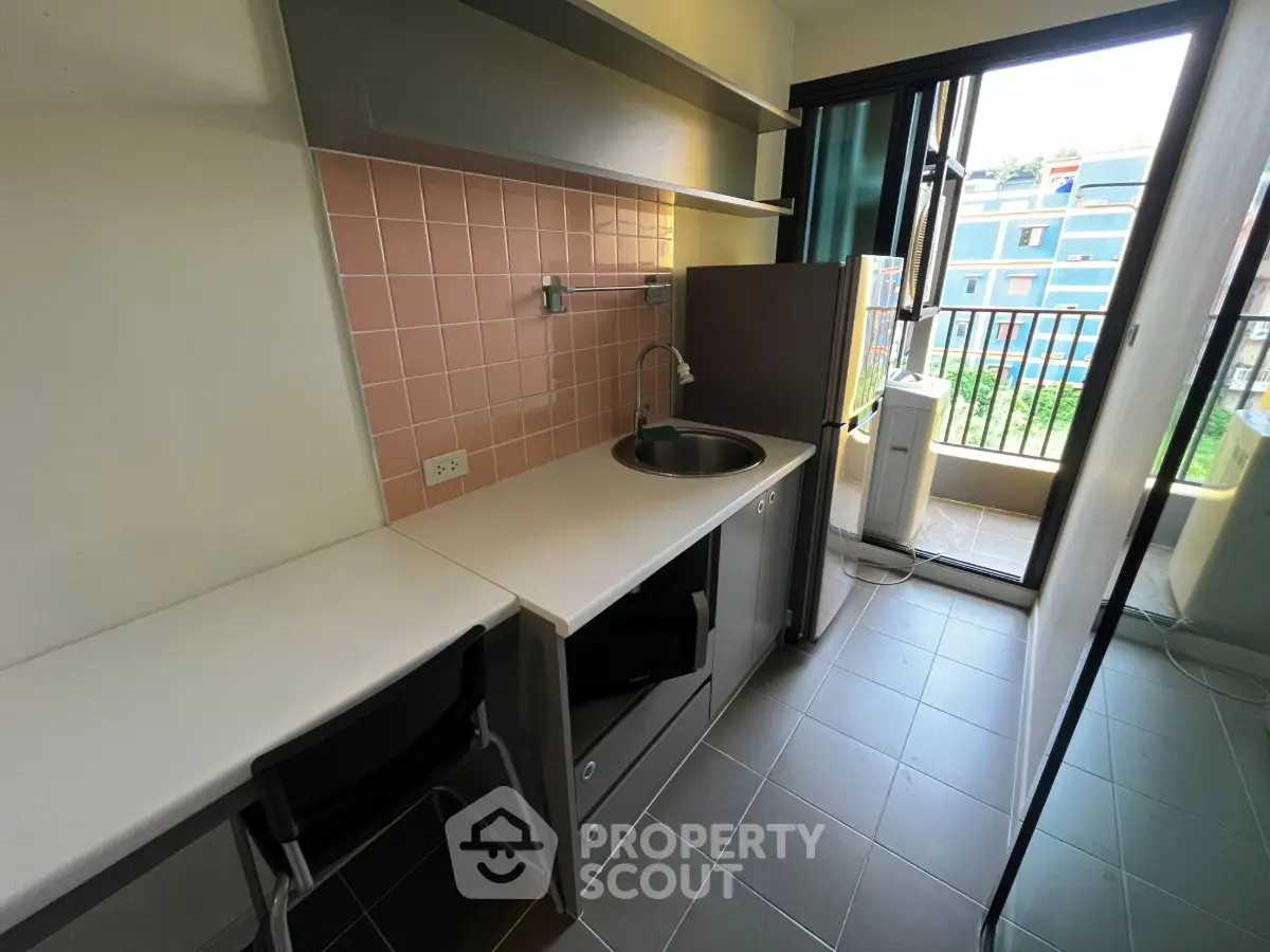 Modern compact kitchen with balcony view in urban apartment